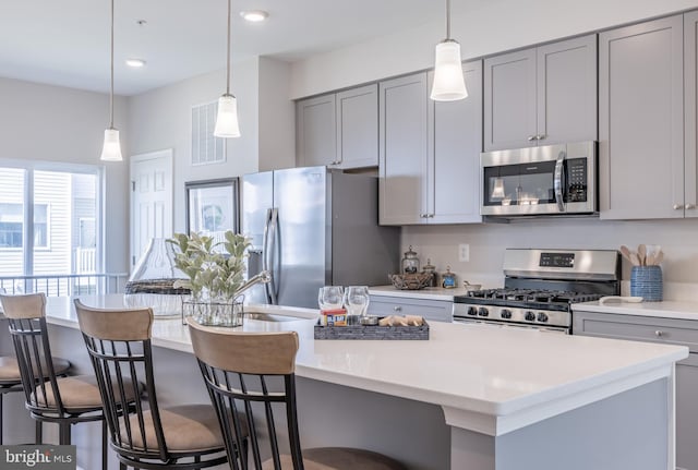 kitchen featuring a kitchen island with sink, appliances with stainless steel finishes, and gray cabinetry