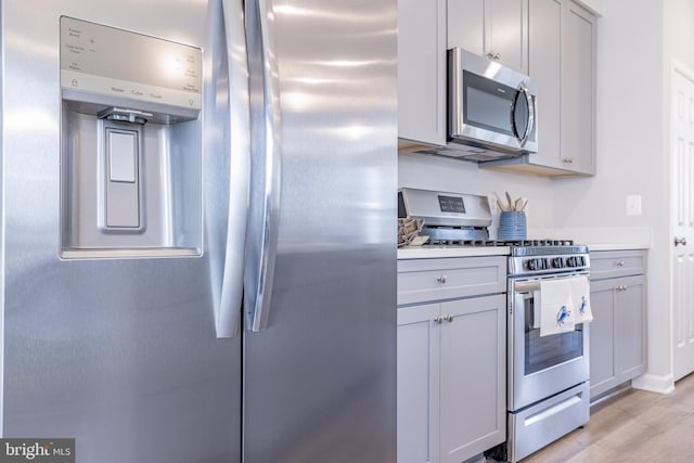 kitchen with gray cabinets, stainless steel appliances, and light wood-type flooring