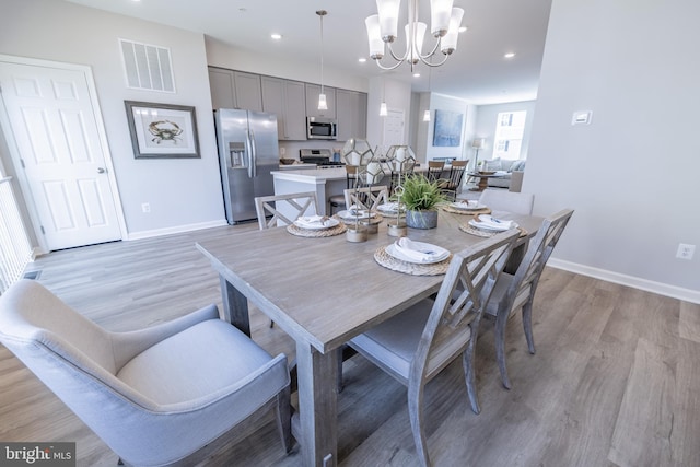 dining space with light hardwood / wood-style floors and a chandelier