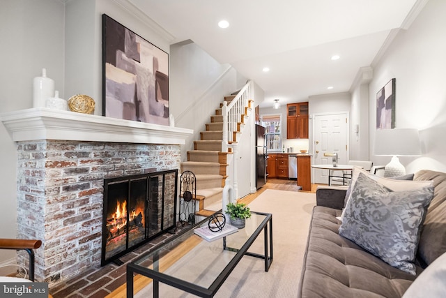 living room with a fireplace, light hardwood / wood-style flooring, and ornamental molding