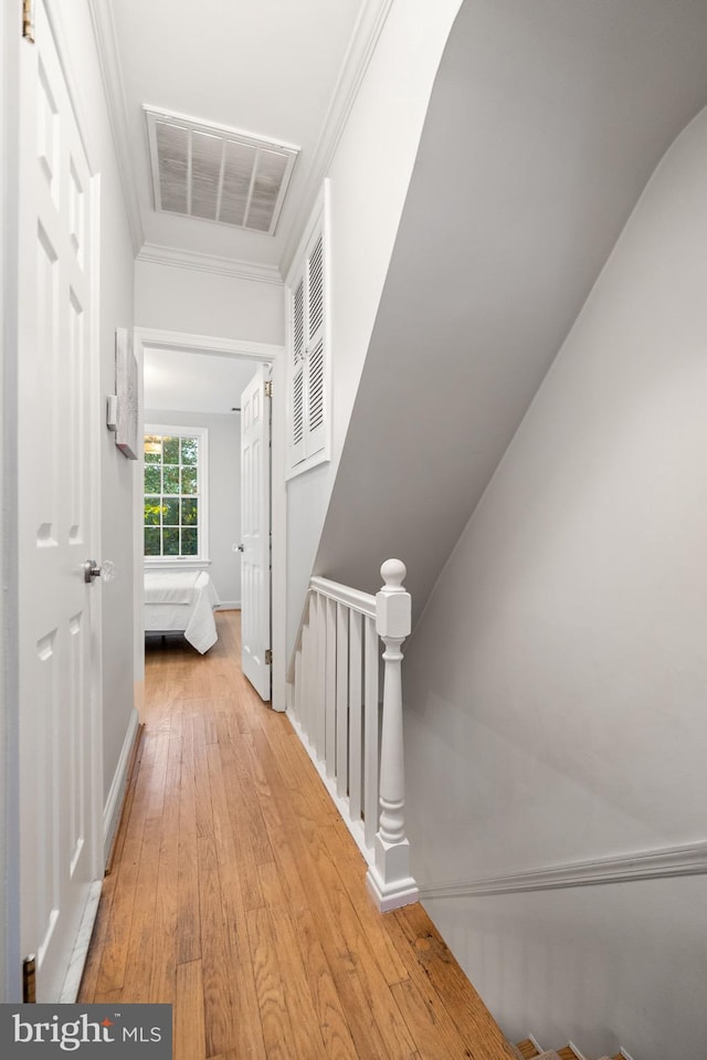 corridor with light hardwood / wood-style flooring and ornamental molding