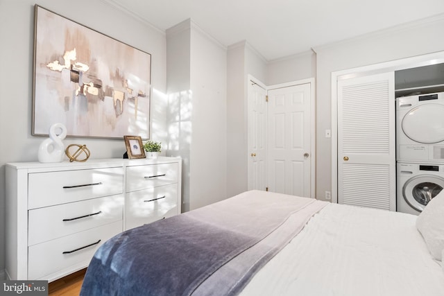 bedroom featuring ornamental molding, stacked washer / drying machine, and wood-type flooring