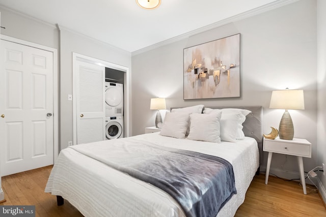 bedroom with stacked washer and dryer, hardwood / wood-style floors, and ornamental molding