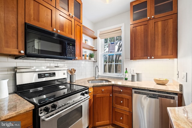 kitchen with tasteful backsplash, light stone counters, sink, and appliances with stainless steel finishes