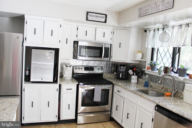 kitchen featuring light stone counters, white cabinets, sink, backsplash, and appliances with stainless steel finishes