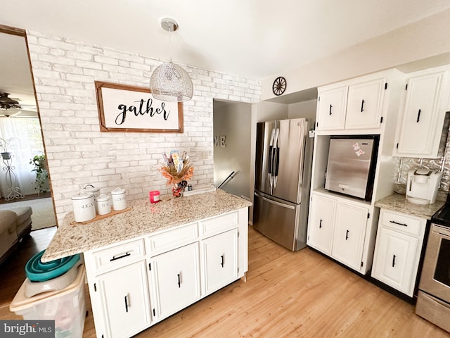 kitchen featuring pendant lighting, stainless steel appliances, light wood-type flooring, and white cabinetry