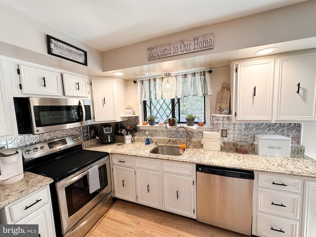 kitchen with light wood-type flooring, sink, stainless steel appliances, and white cabinets