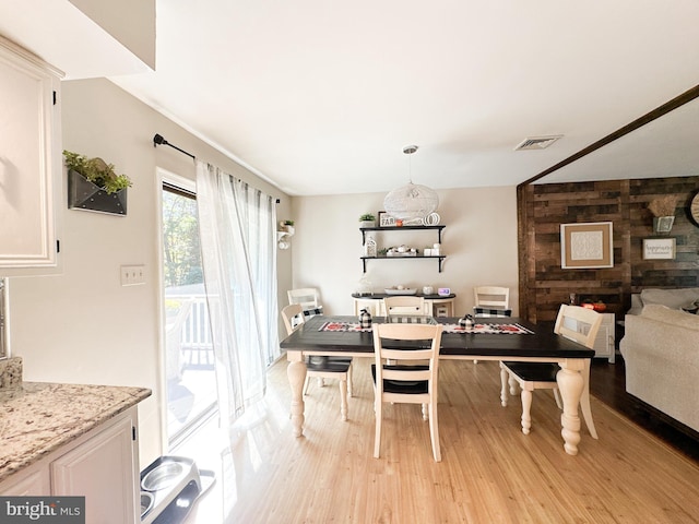 dining room with light wood-type flooring and wood walls