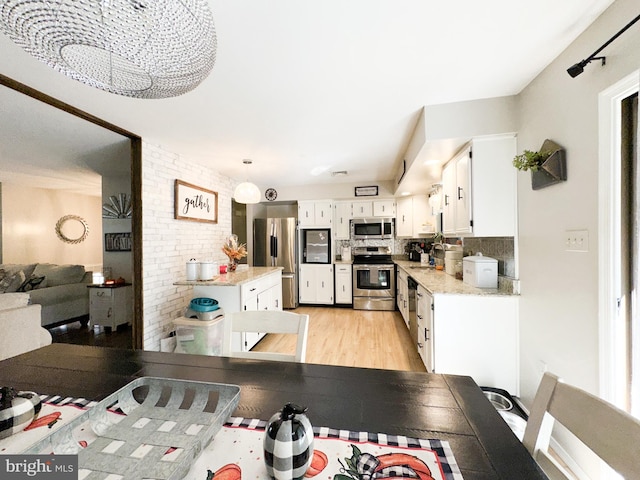 dining space with brick wall and light wood-type flooring