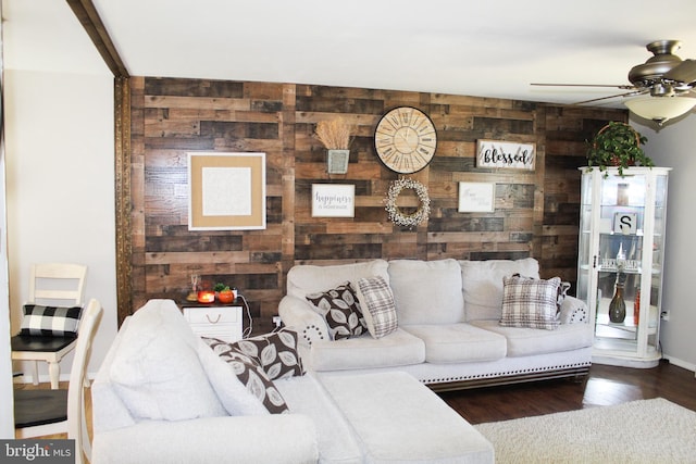 living room featuring hardwood / wood-style flooring, wooden walls, and ceiling fan