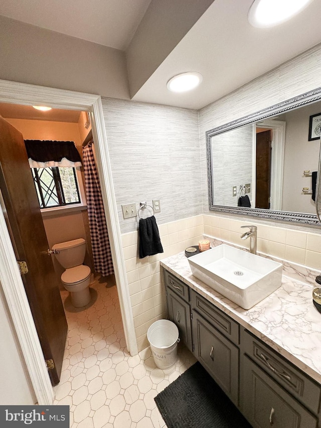 bathroom with tile patterned flooring, tile walls, vanity, and toilet