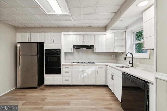 kitchen featuring appliances with stainless steel finishes, sink, light wood-type flooring, and white cabinetry