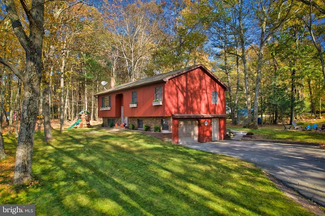 view of front of house featuring a garage, a front lawn, and a playground