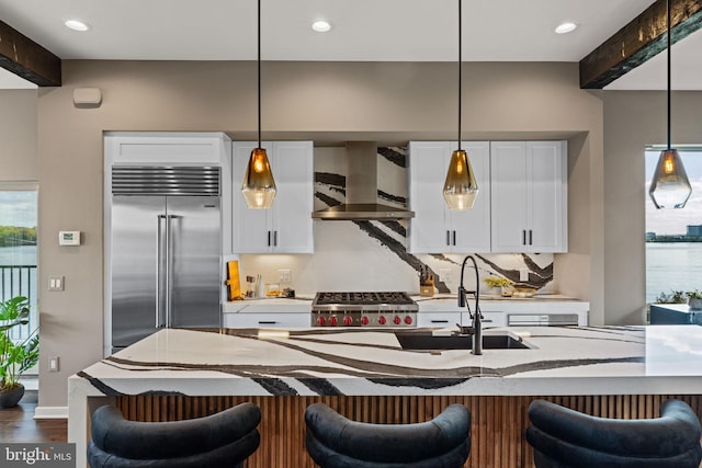 kitchen featuring stainless steel appliances, a water view, wall chimney exhaust hood, and beamed ceiling