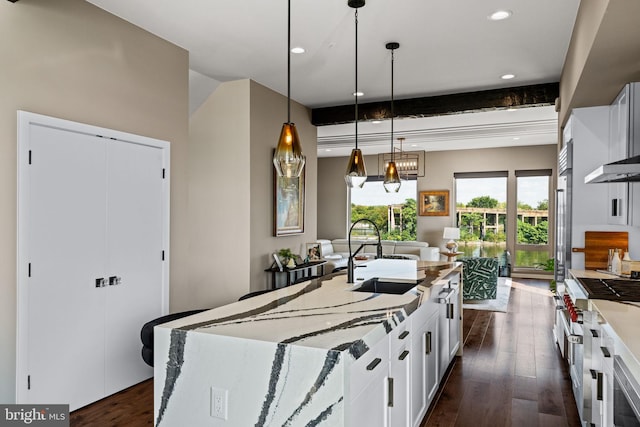 kitchen with hanging light fixtures, beam ceiling, sink, and white cabinetry