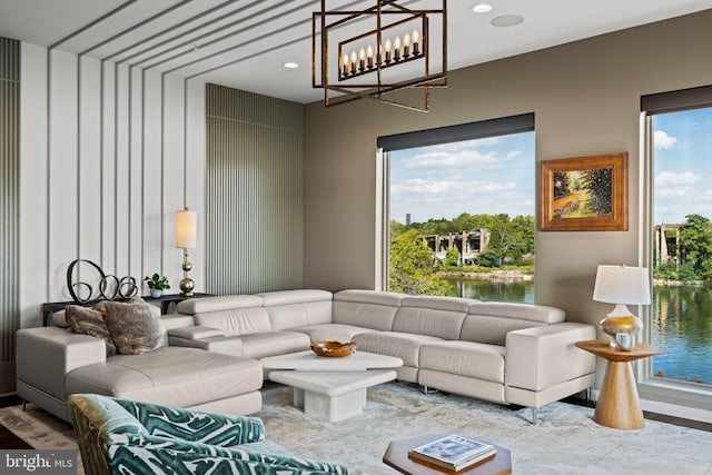 living room with wood-type flooring, a notable chandelier, plenty of natural light, and a water view