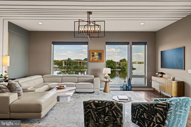 living room with a water view, hardwood / wood-style floors, and an inviting chandelier