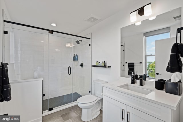 bathroom with vanity, toilet, and a shower with door