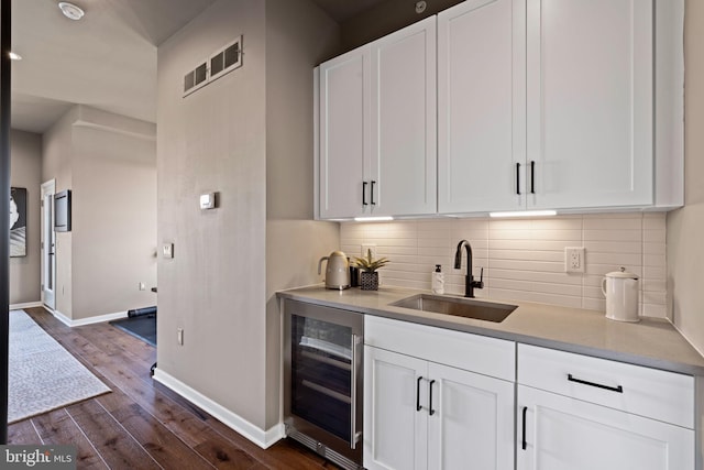 bar featuring wine cooler, sink, dark hardwood / wood-style flooring, and white cabinetry