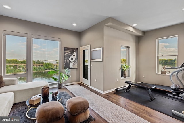 exercise area with dark wood-type flooring and a water view