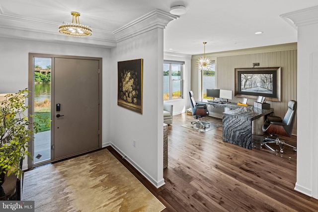 foyer entrance with crown molding, a wealth of natural light, an inviting chandelier, and dark hardwood / wood-style flooring