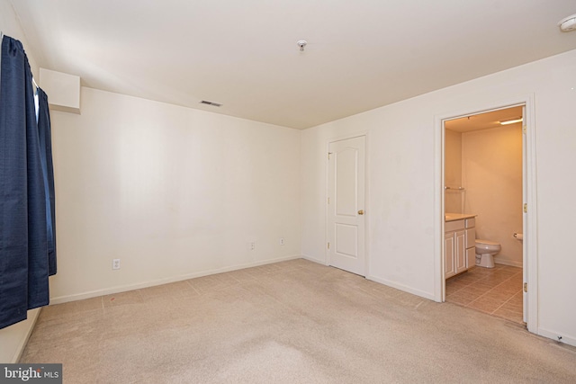 unfurnished bedroom featuring ensuite bath and light carpet