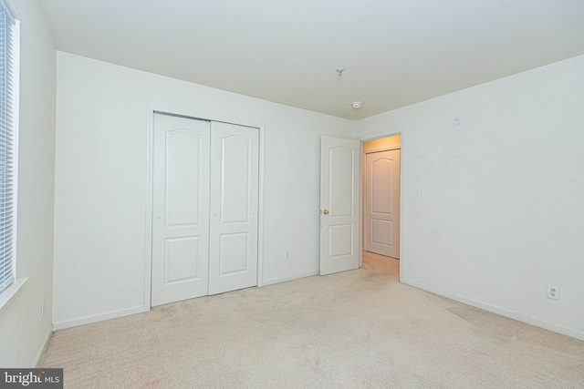 unfurnished bedroom featuring a closet and light colored carpet