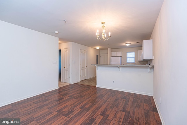 kitchen featuring a kitchen bar, dark hardwood / wood-style flooring, kitchen peninsula, white cabinets, and white fridge