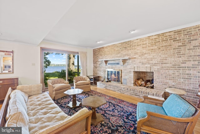 living room featuring ornamental molding, hardwood / wood-style flooring, brick wall, and a fireplace