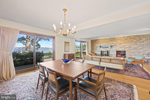 dining area featuring hardwood / wood-style flooring, brick wall, an inviting chandelier, and a fireplace