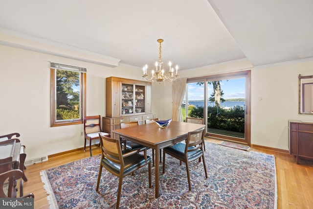 dining area with crown molding, light hardwood / wood-style flooring, and an inviting chandelier