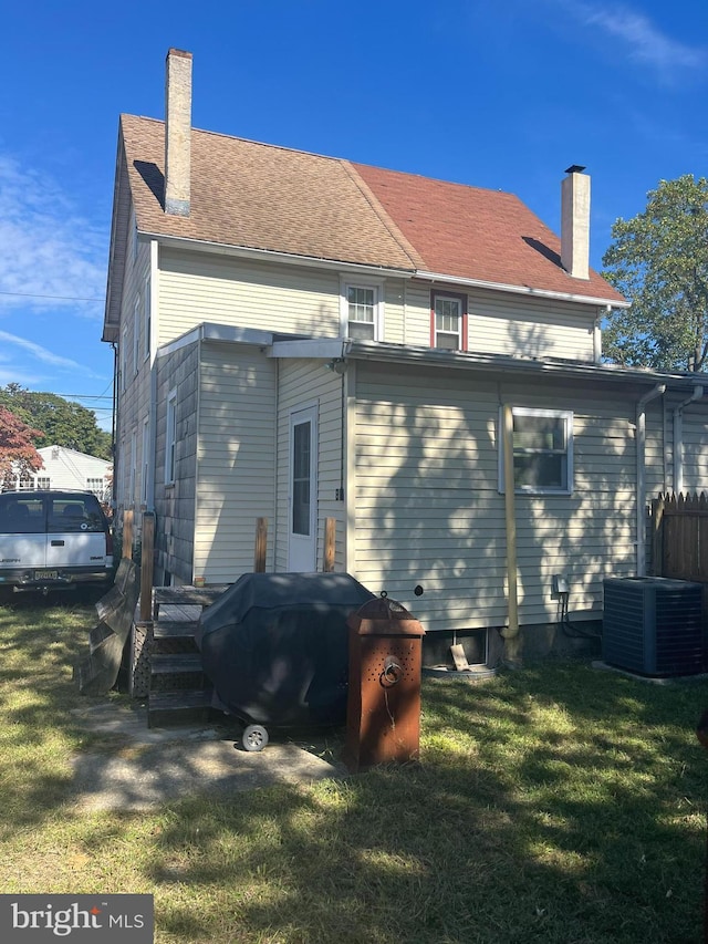 rear view of property featuring a lawn and central AC unit