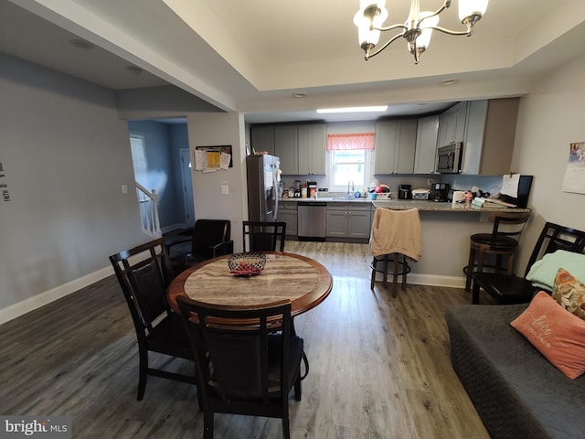 dining room featuring a tray ceiling, dark hardwood / wood-style floors, sink, and a chandelier