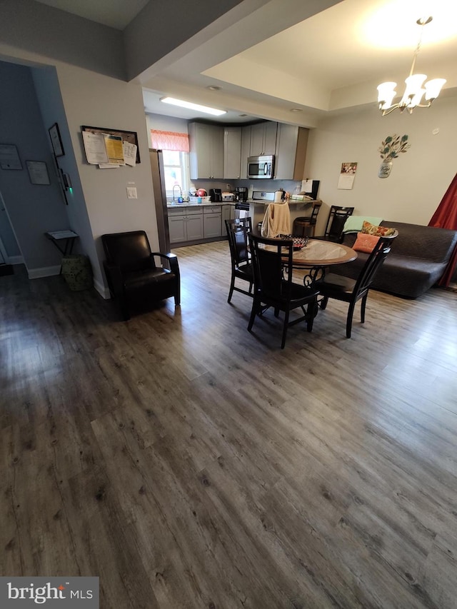 dining area featuring a chandelier, a raised ceiling, and dark hardwood / wood-style flooring