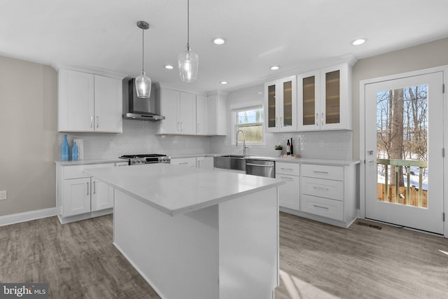 kitchen featuring a center island, white cabinetry, wall chimney range hood, and dishwasher