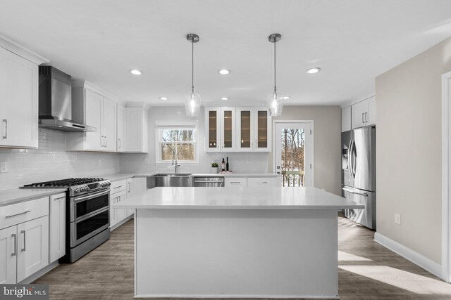 kitchen with appliances with stainless steel finishes, a center island, sink, and wall chimney exhaust hood