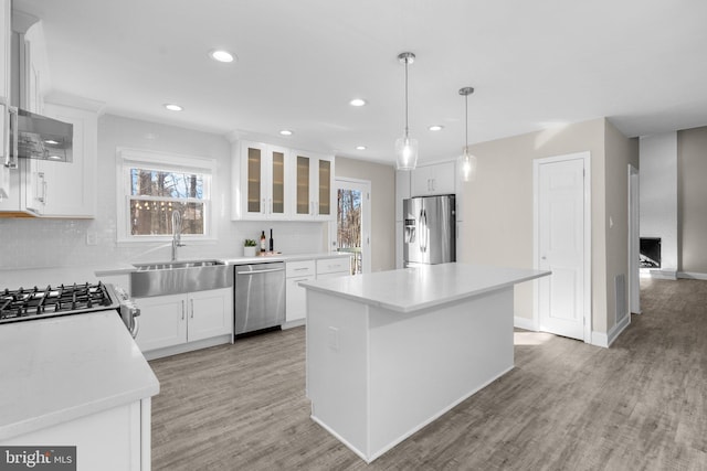 kitchen featuring stainless steel appliances, sink, a center island, white cabinetry, and backsplash