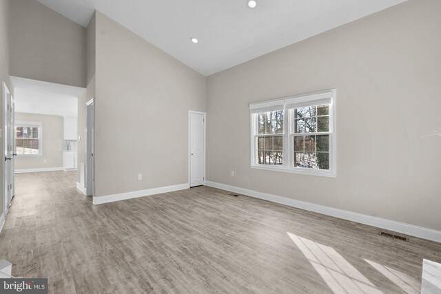 empty room with light hardwood / wood-style flooring and high vaulted ceiling