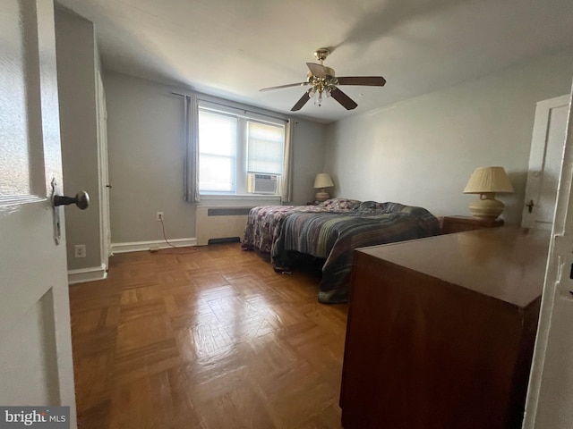 bedroom with ceiling fan, cooling unit, parquet flooring, and radiator heating unit