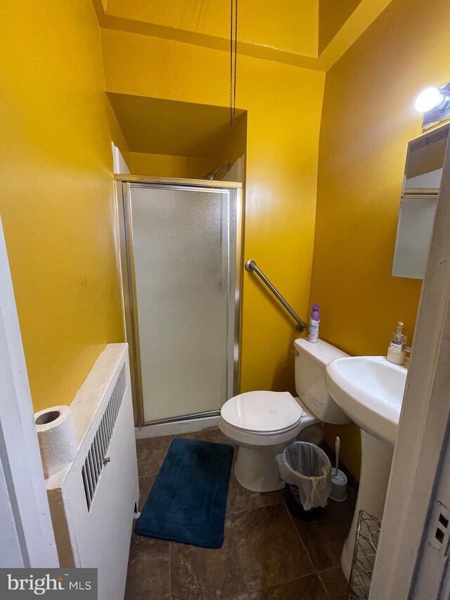 bathroom with tile patterned flooring, toilet, and an enclosed shower