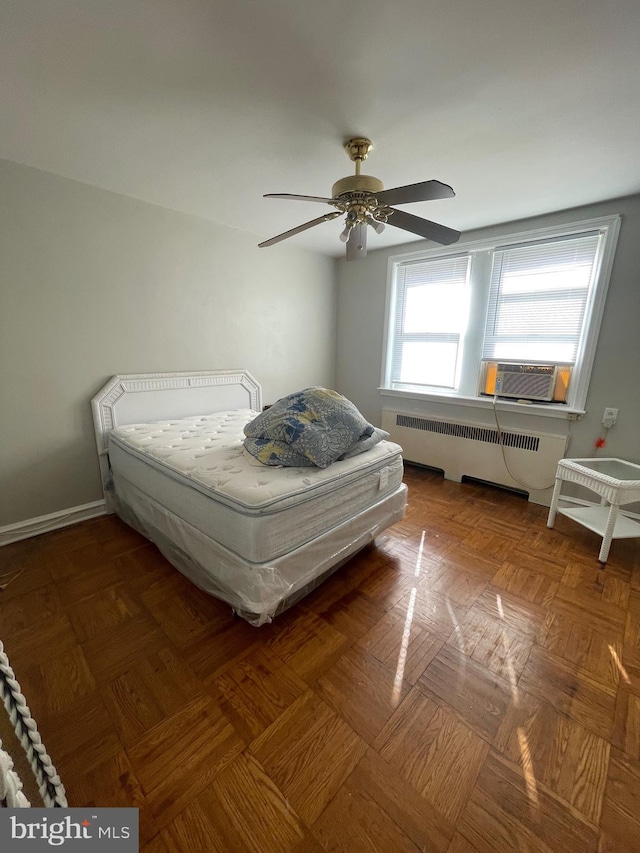 bedroom featuring cooling unit, ceiling fan, radiator heating unit, and dark parquet flooring