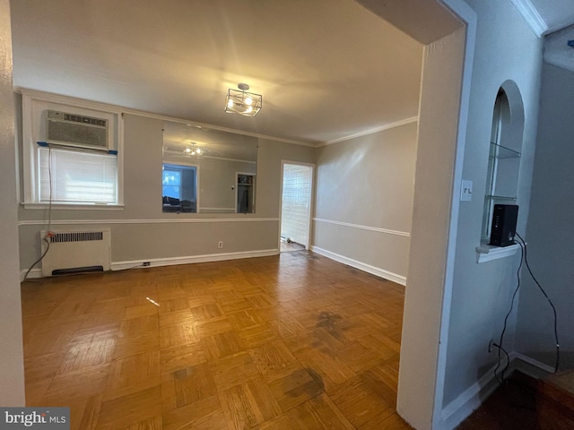 unfurnished room with a healthy amount of sunlight, a wall unit AC, radiator, and crown molding