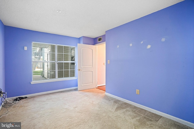 empty room featuring a textured ceiling and carpet