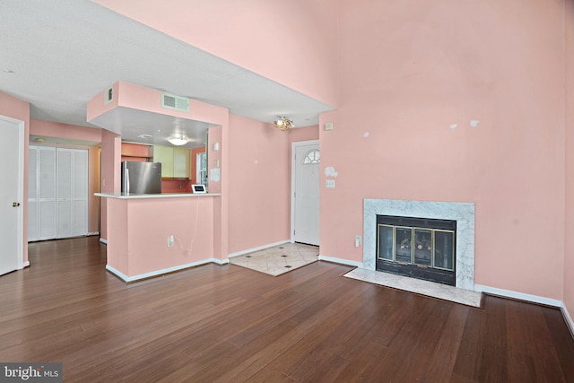 unfurnished living room featuring a premium fireplace, hardwood / wood-style floors, and a textured ceiling