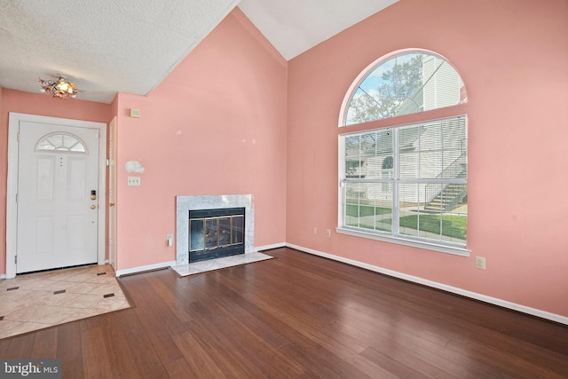 unfurnished living room with a fireplace, hardwood / wood-style flooring, a wealth of natural light, and a textured ceiling