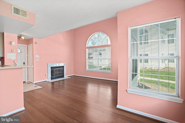 unfurnished living room featuring plenty of natural light, dark hardwood / wood-style flooring, and a textured ceiling