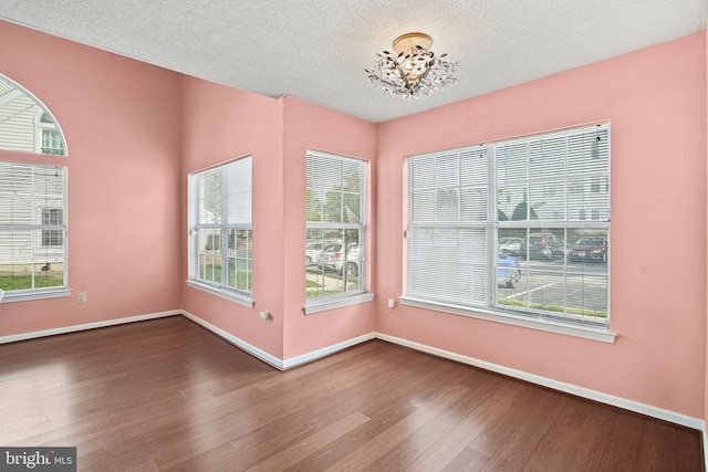 unfurnished room featuring hardwood / wood-style flooring, a notable chandelier, and a healthy amount of sunlight