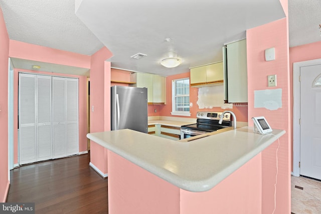 kitchen with kitchen peninsula, appliances with stainless steel finishes, hardwood / wood-style flooring, and a textured ceiling