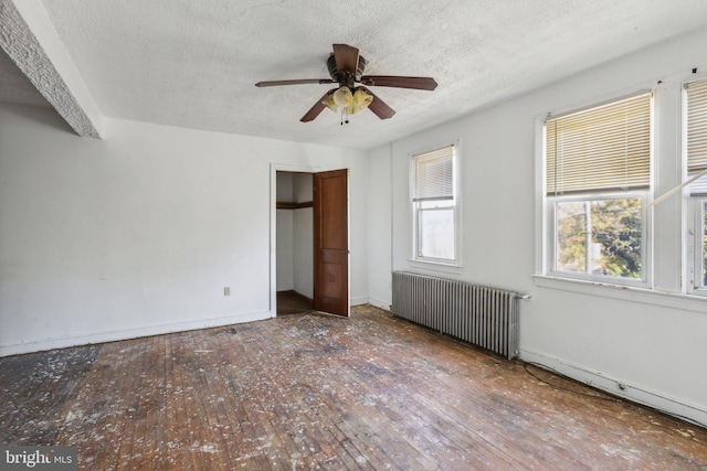 unfurnished bedroom with a textured ceiling, wood-type flooring, radiator, and ceiling fan