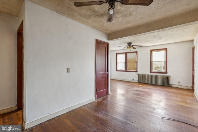 unfurnished room with ceiling fan, hardwood / wood-style flooring, a textured ceiling, and radiator heating unit